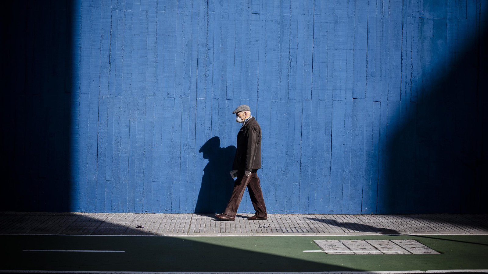 Un hombre camina protegido con mascarilla.