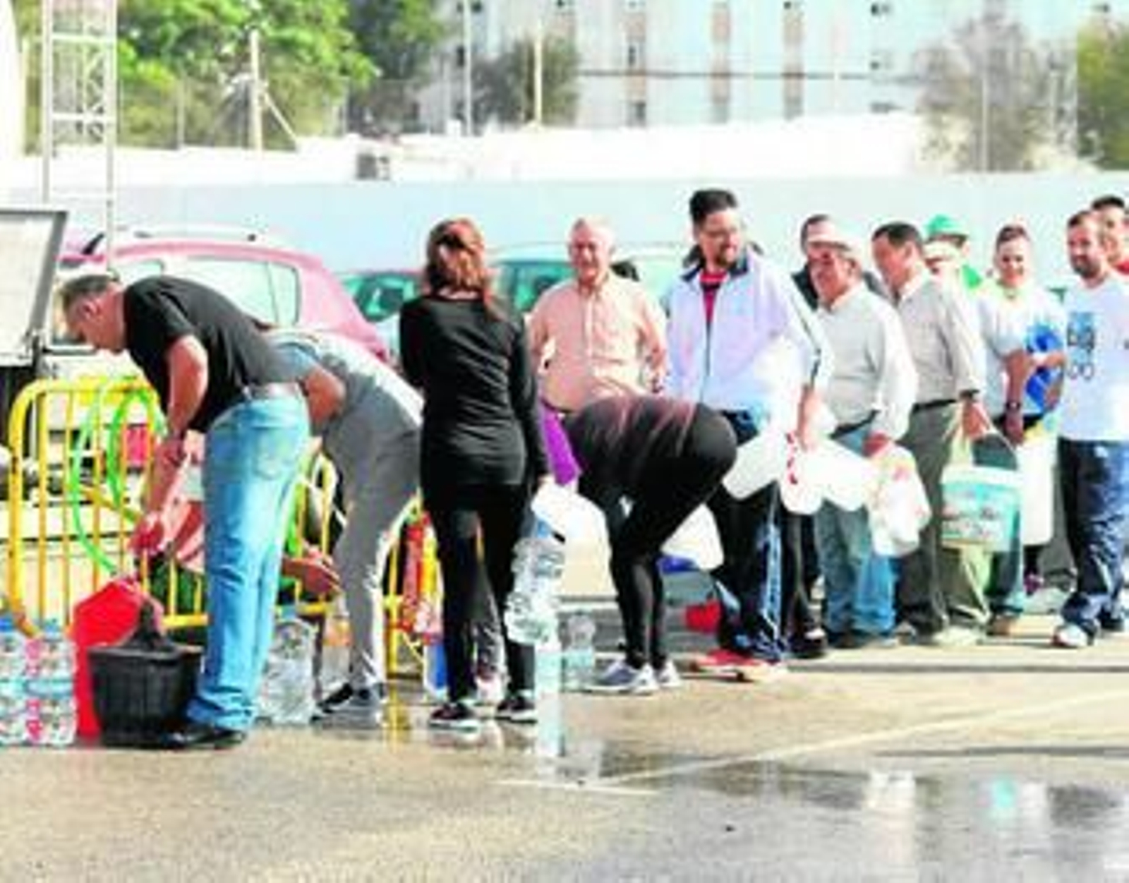 Varios vecinos hacen cola ante una fuente de Medina en la que se informa de que no es apta para el consumo humano.