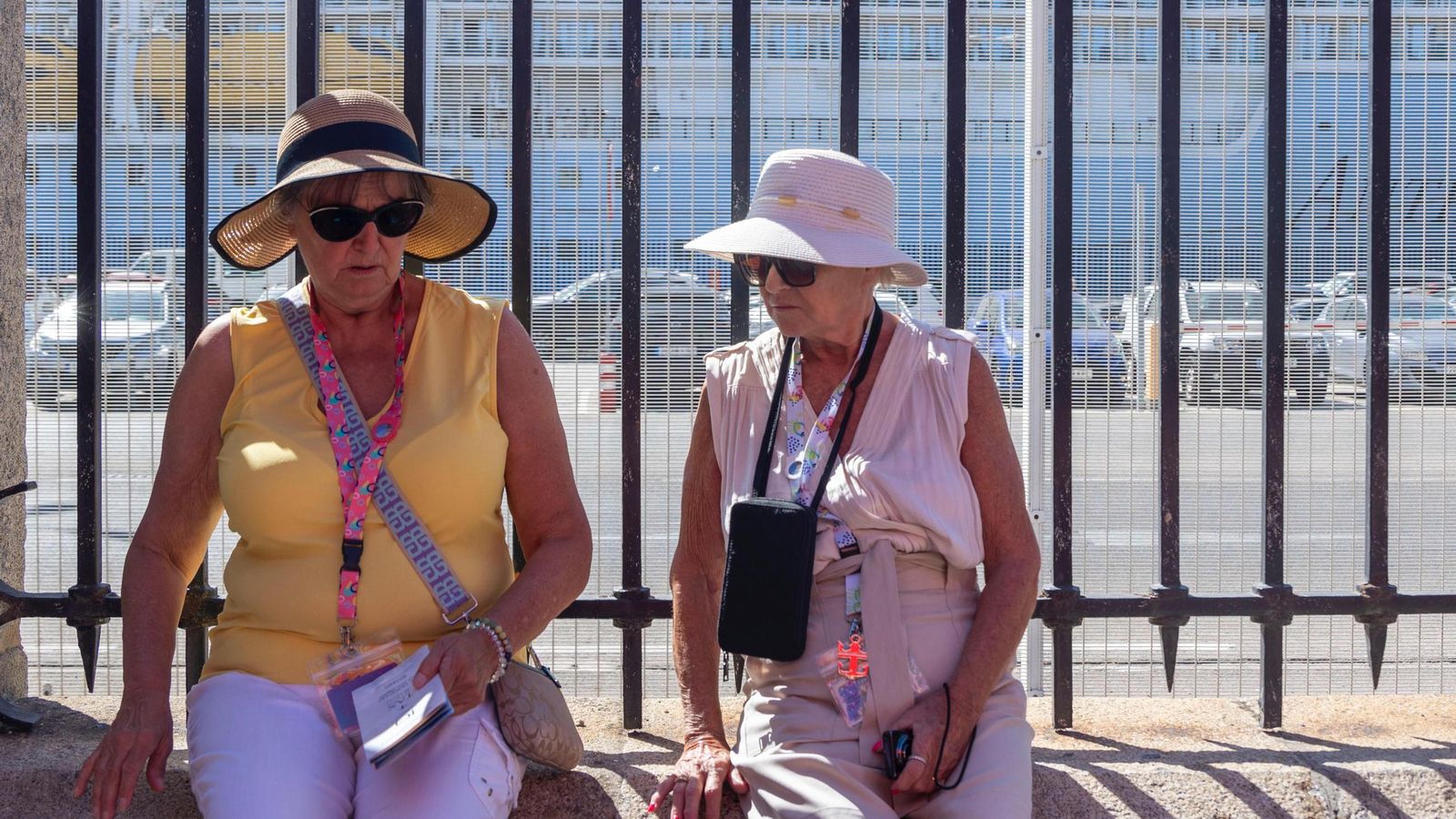 Dos señoras, sentadas junto a la verja del muelle del puerto de Cádiz tomándose un respiro