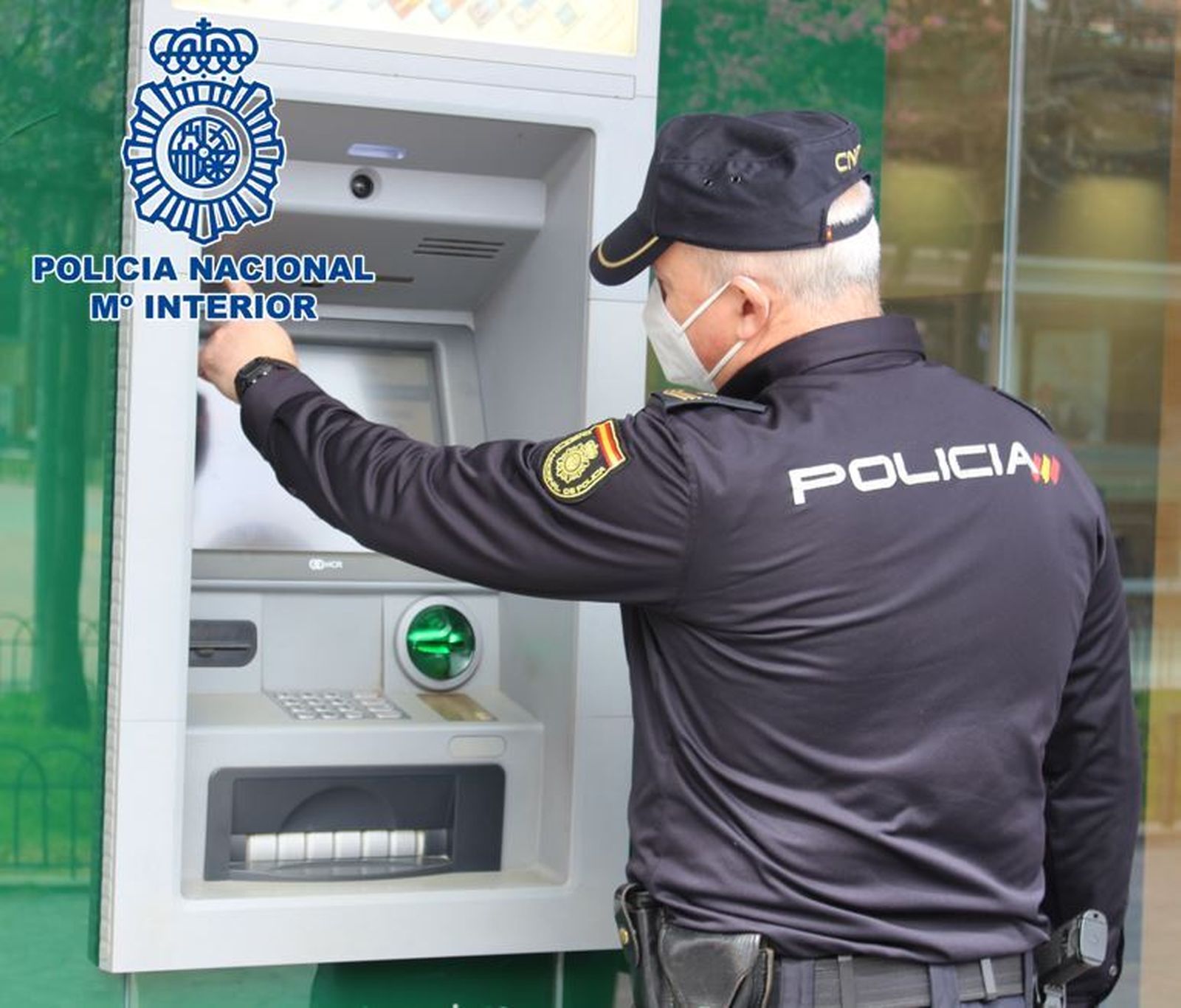 Un agente de la Policía Nacional junto al cajero de un banco.