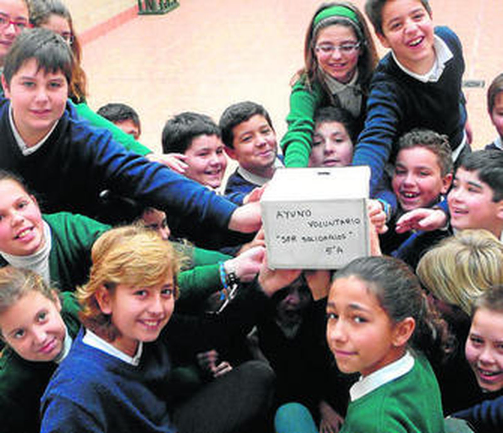 Los escolares muestran la hucha con el dinero para Manos Unidas.