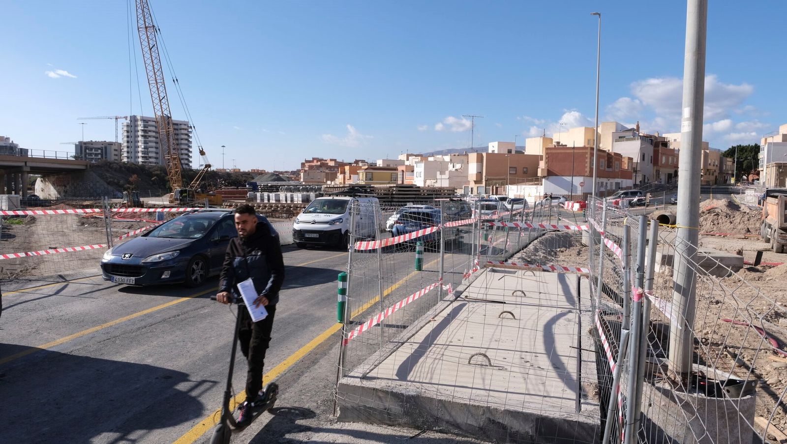 Un joven en patinete cruza por las obras del soterramiento.