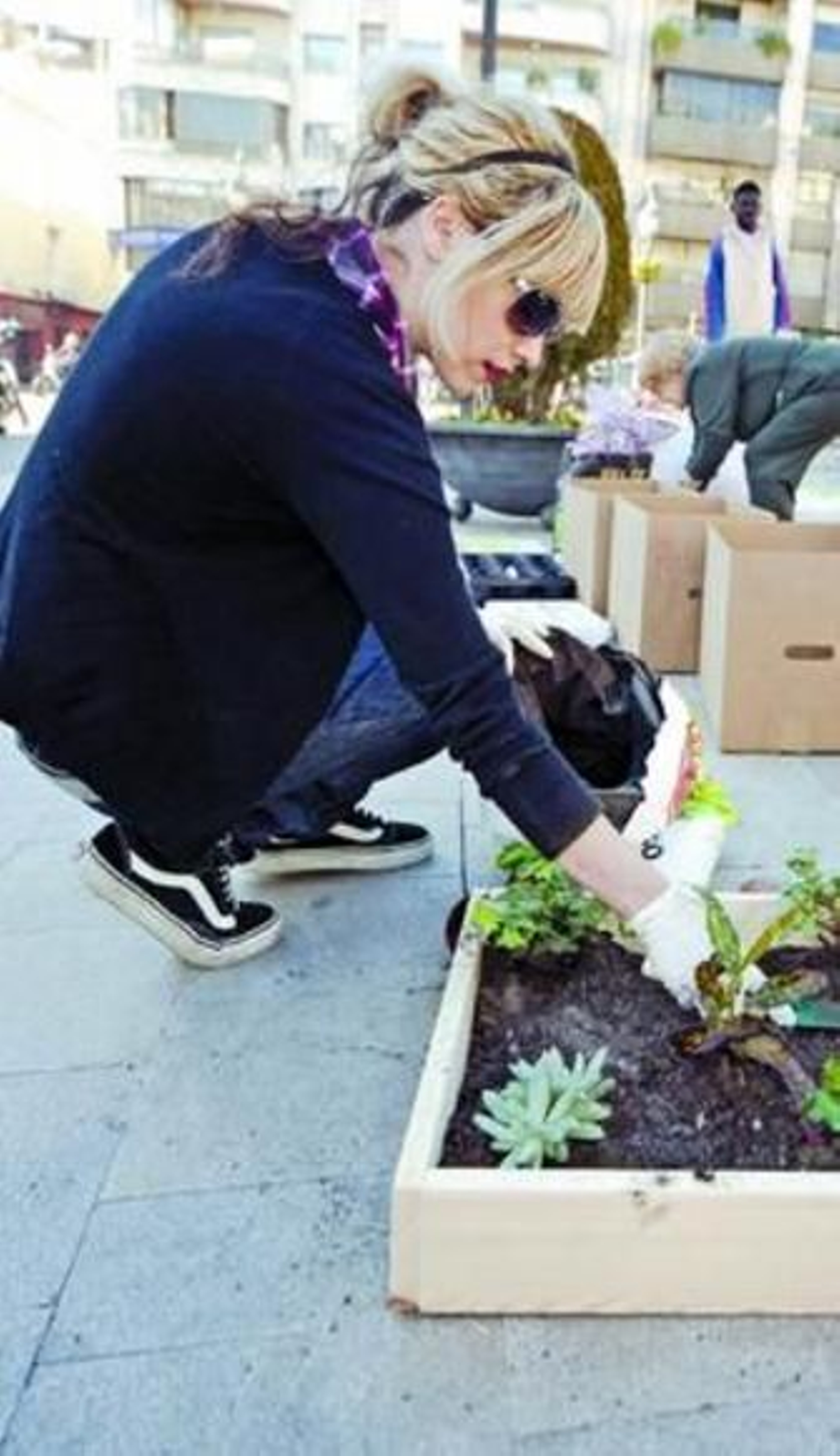 Una chica planta flores en una jardinera portátil.