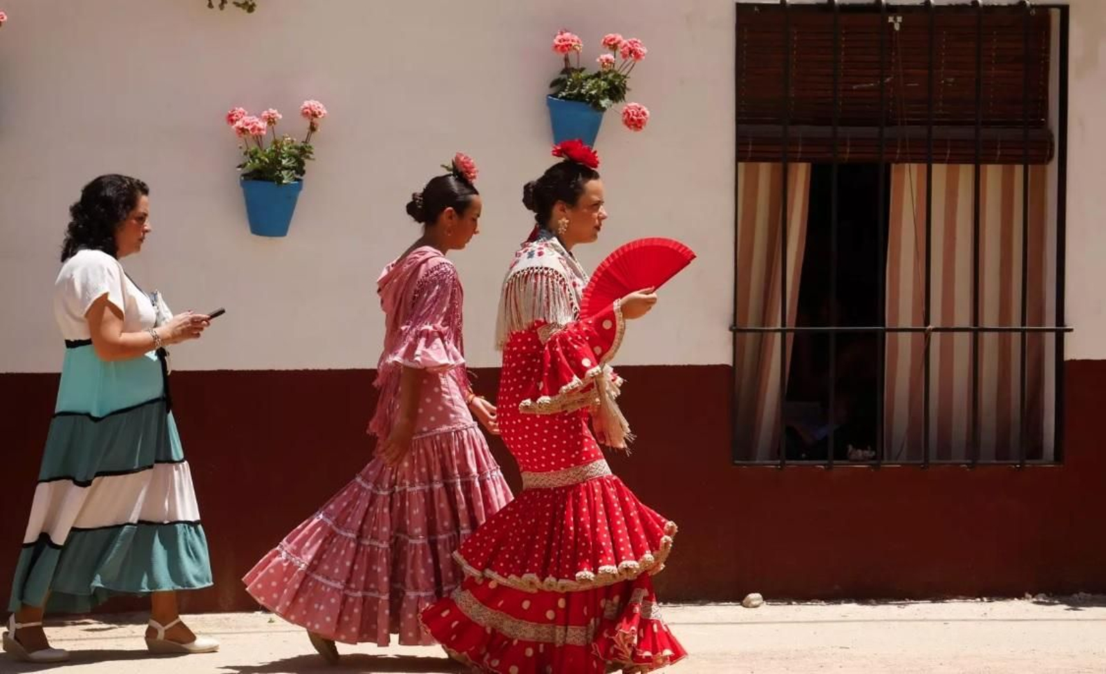 Una mujer vestida de flamenca se abanica en la Feria de Córdoba.