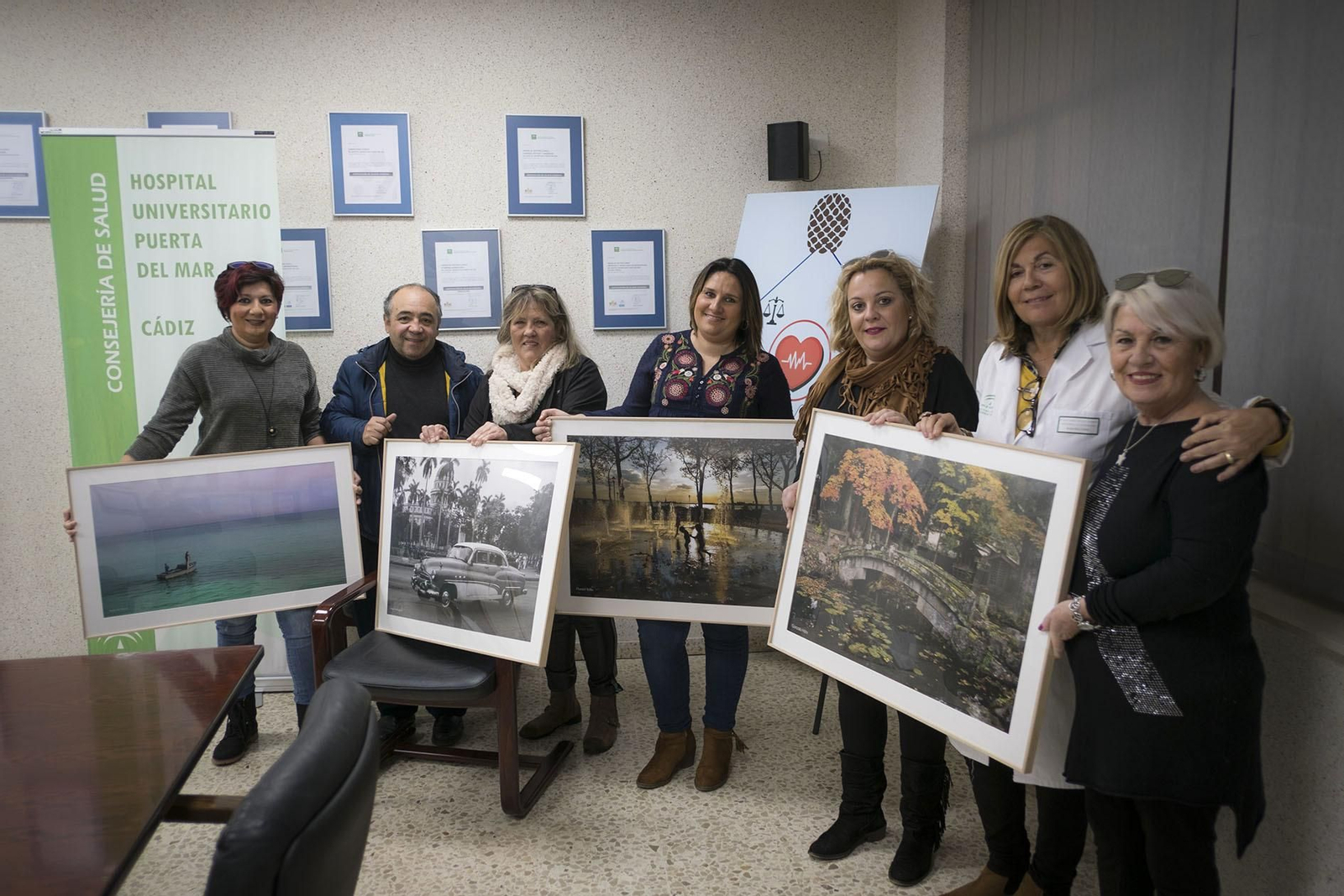 Mujeres de la asociación junto a Kiki y la subdirectora de Atención a la Ciudadanía del hospital muestran algunas fotos donadas.