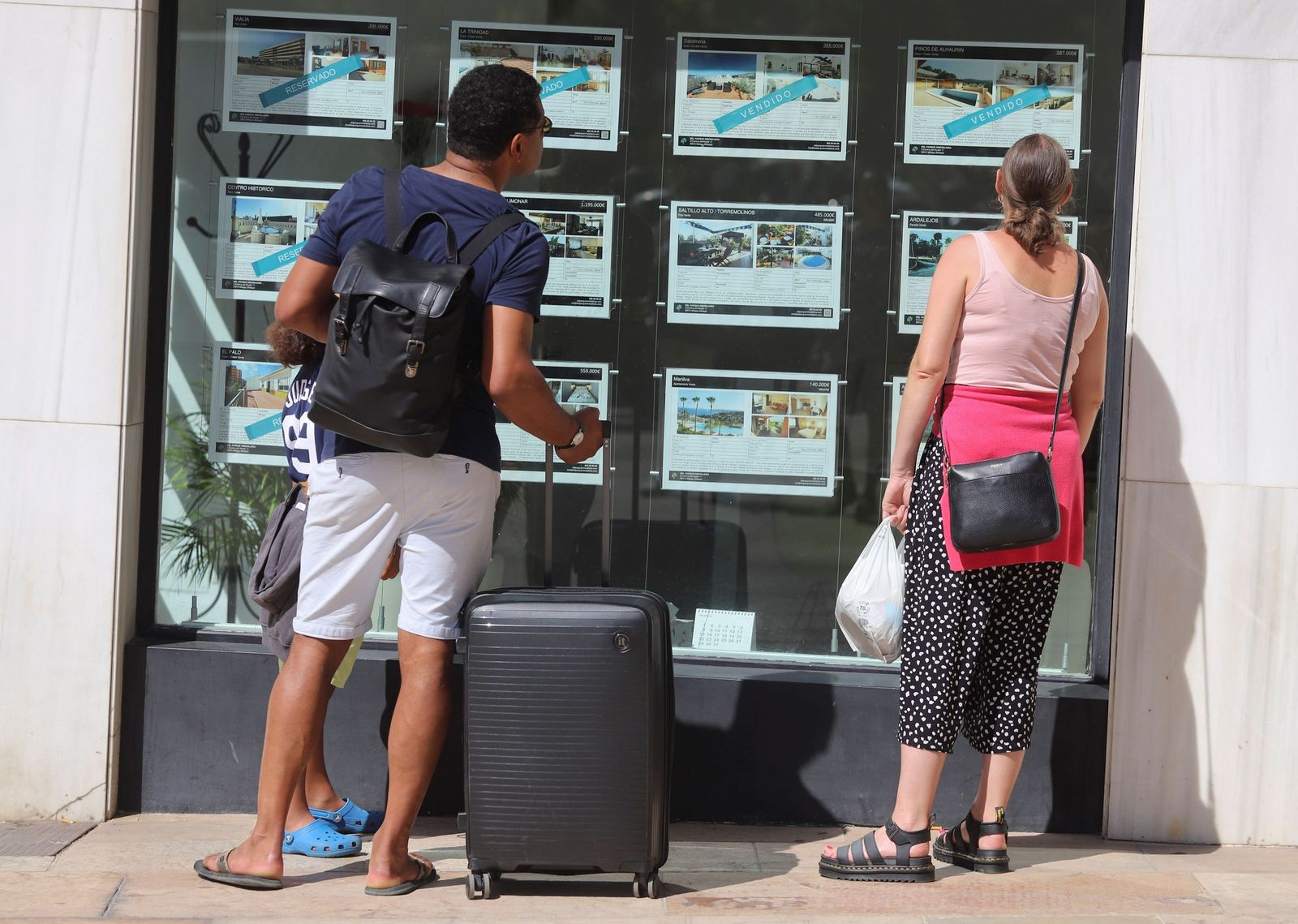 Dos personas mirando un escaparate de una inmobiliaria en la capital malagueña.