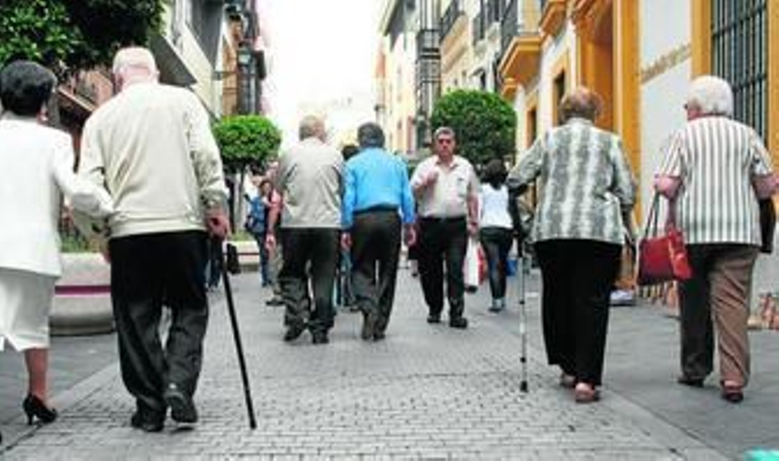 Varias personas mayores pasean por el centro de Sevilla.