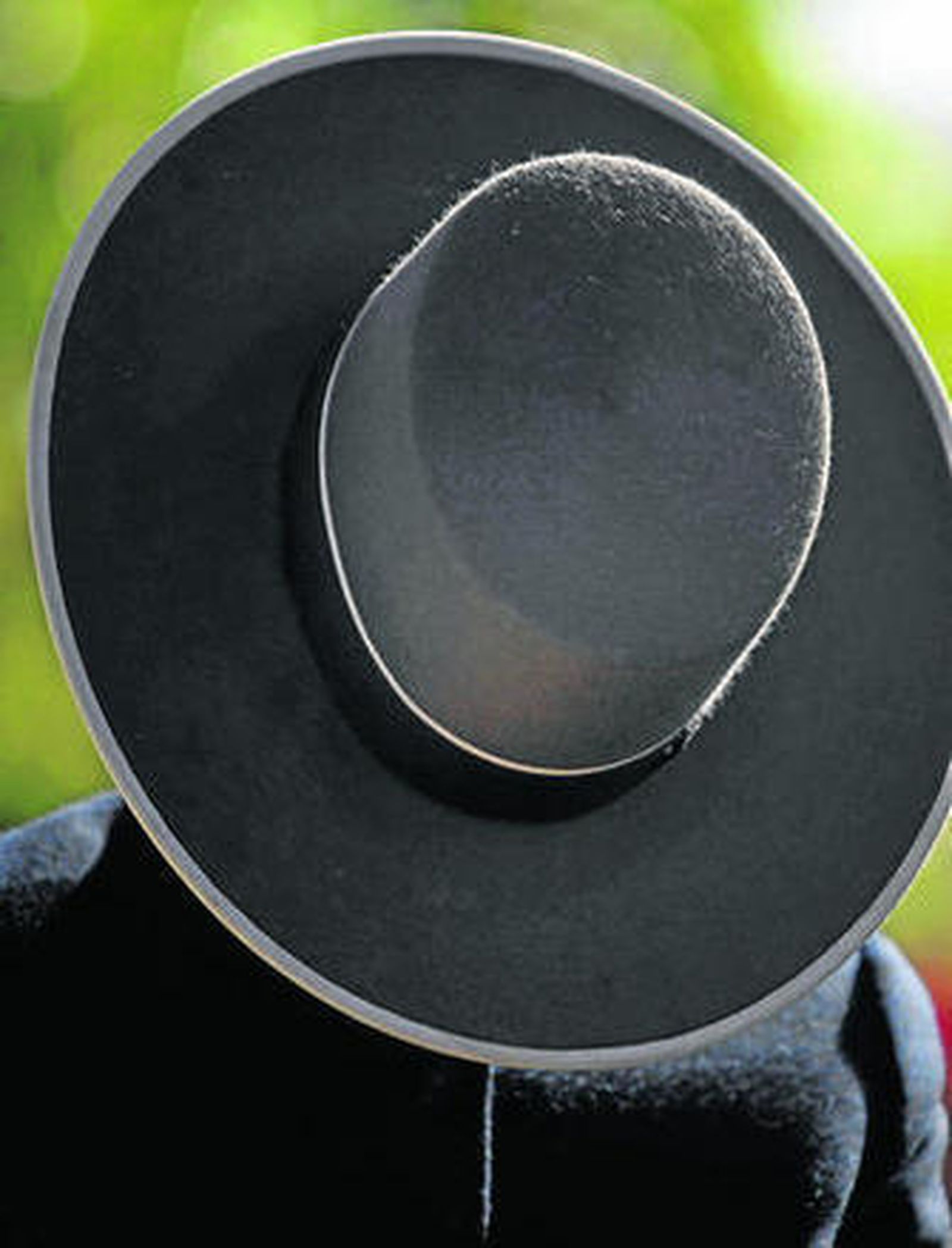 Un caballista, agotado tras el paseo, se tapa con un sombrero.