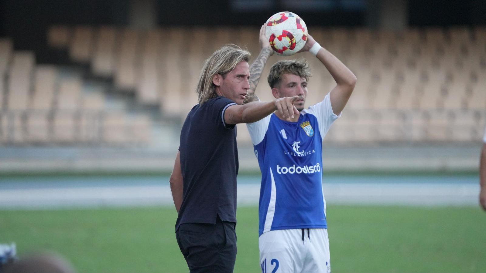 Checa da indicaciones a su equipo mientras Ramón García se dispone a sacar de banda.