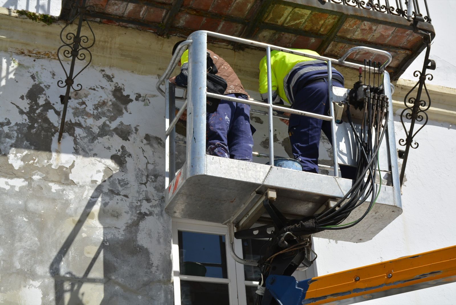 Dos operarios repintan la fachada del Palacio de los Gobernadores de San Roque, en una actuación anterior.