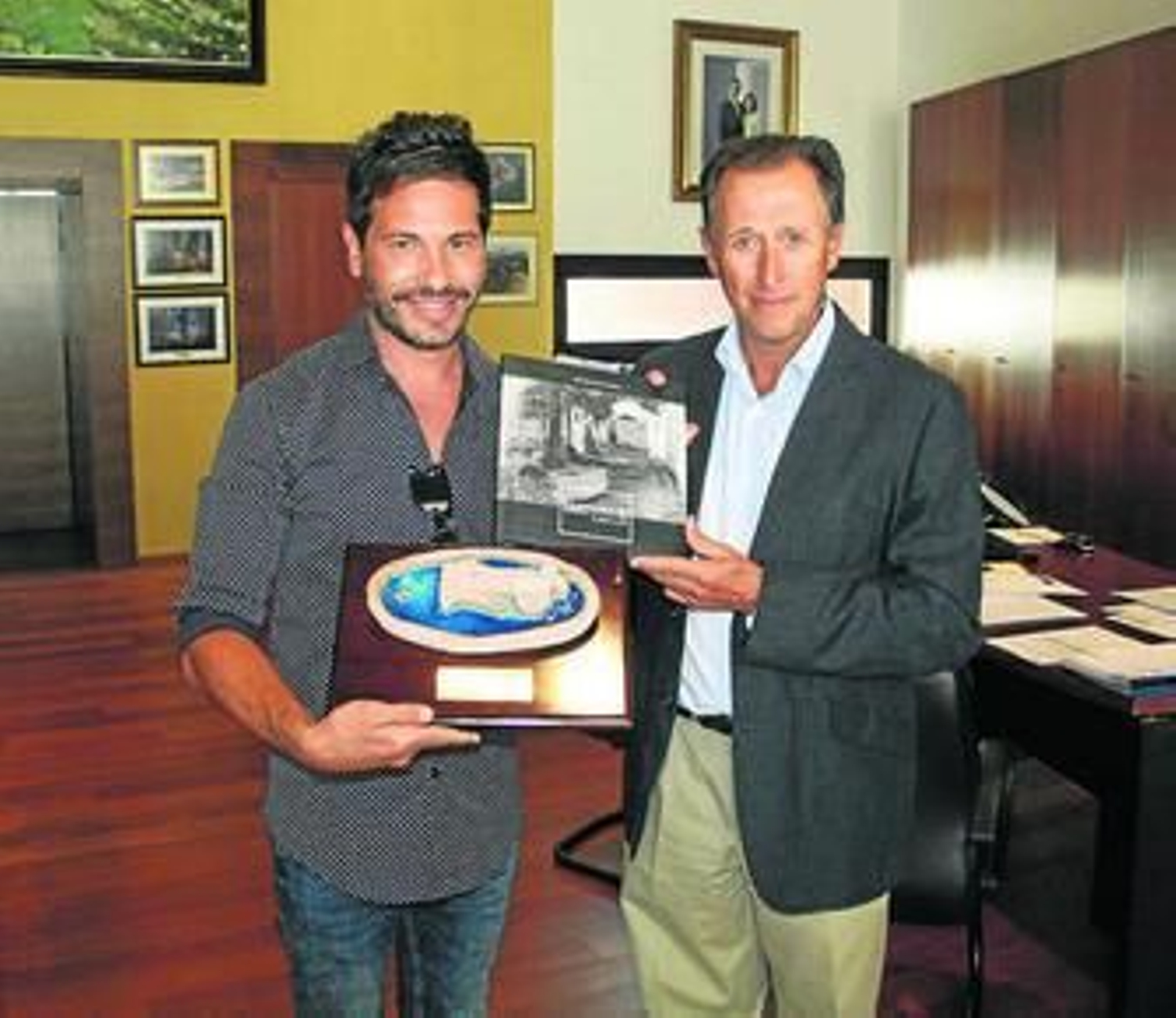 El alcalde hace entrega al cantante de varios obsequios.