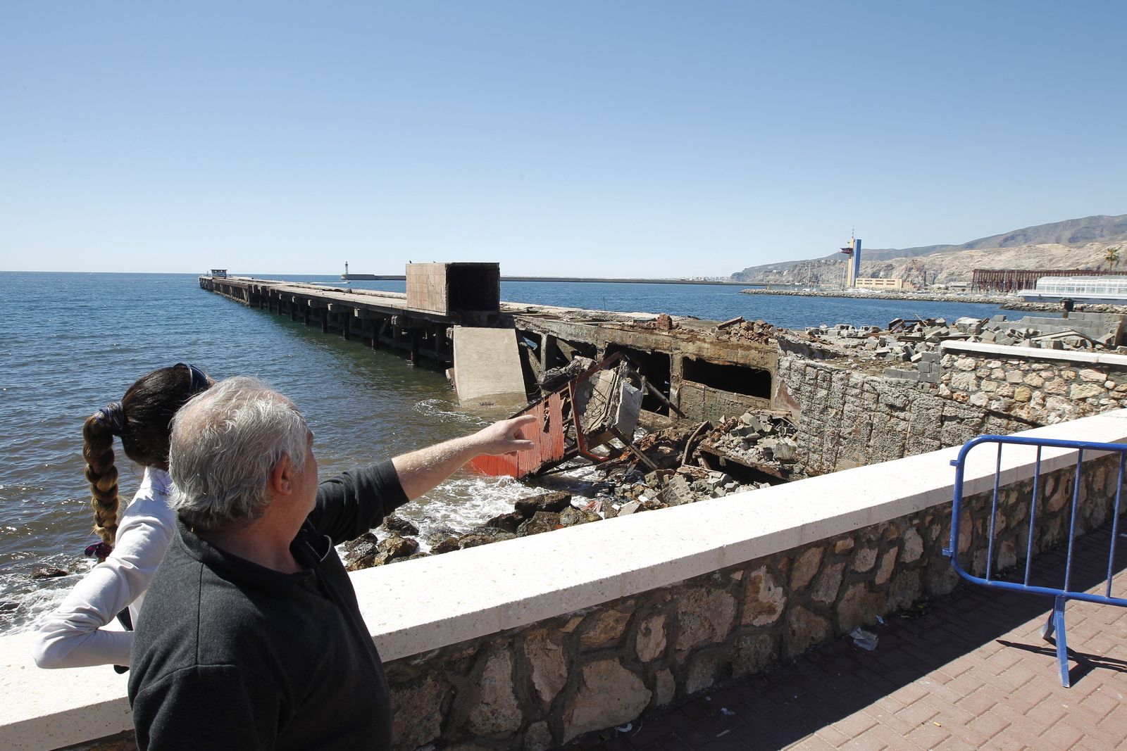 Dos personas observan la caseta y parte del pantalán vencidos.