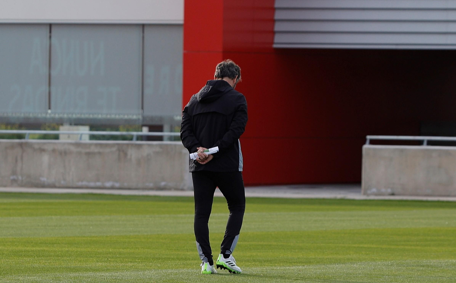 Quique Sánchez Flores, meditabundo, con el nuevo edificio del primer equipo al fondo.