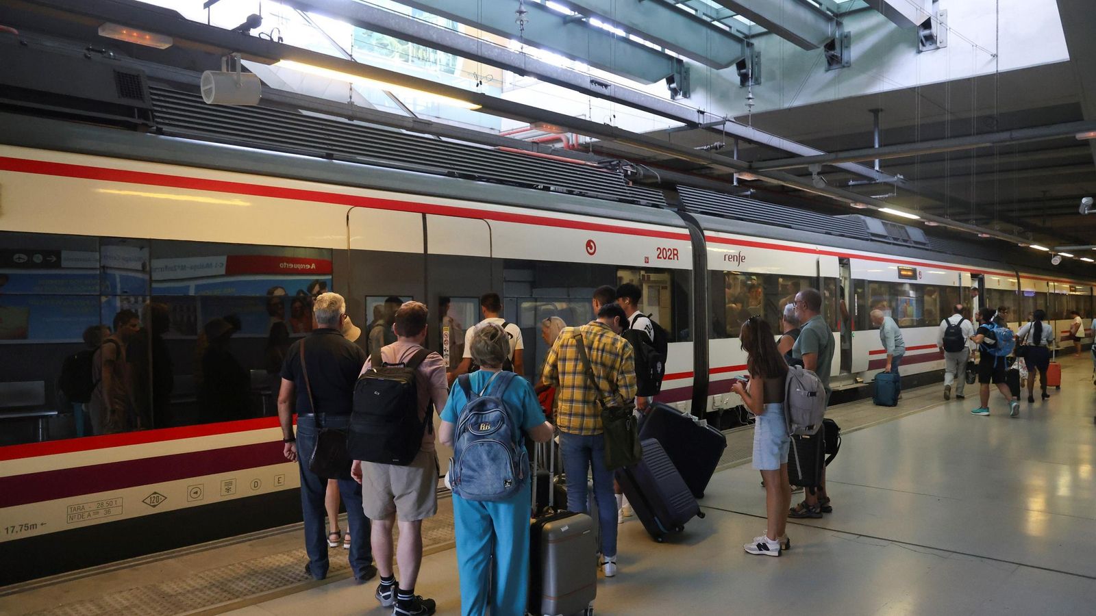 Viajeros esperan para entrar en un tren de Cercanías en el Aeropuerto.