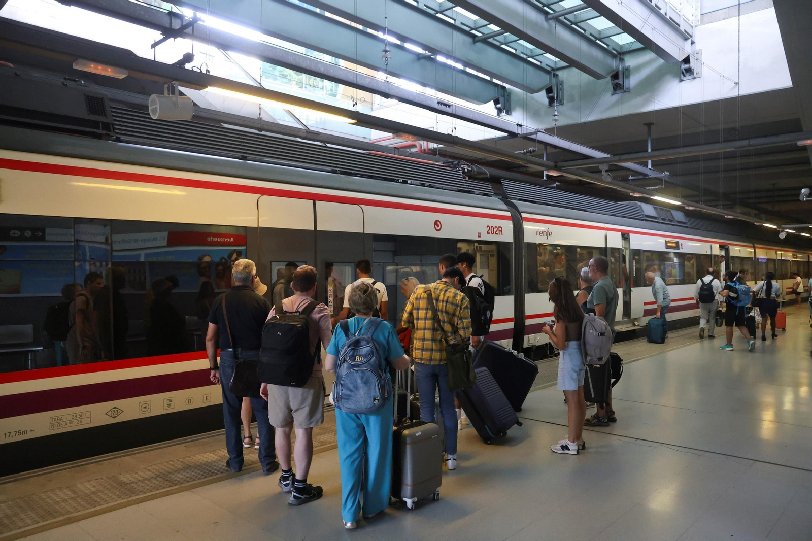 Viajeros esperan para entrar en un tren de Cercanías en el Aeropuerto.