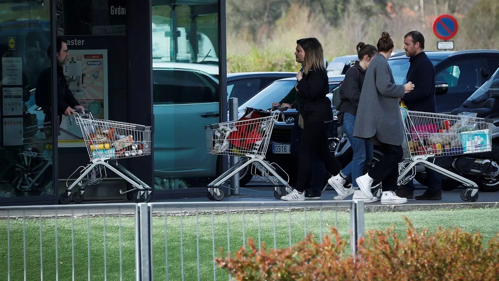Varias personas con carros haciendo la compra.