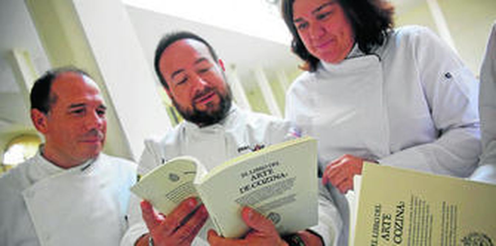 Algunos de los cocineros hojean 'El Libro de Arte de Cozina', minutos antes de la presentación del mismo.