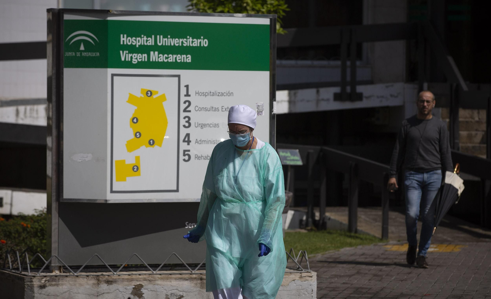 Una sanitaria pasa por delante del cartel que especifica las áreas en las que se divide el Hospital Virgen Macarena.