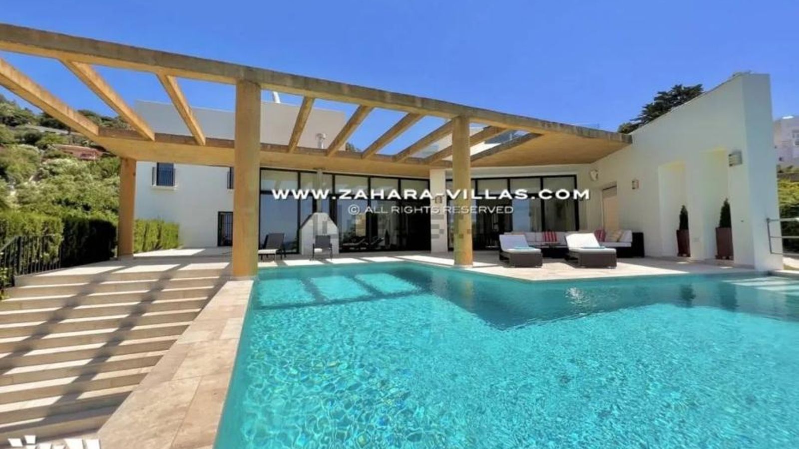 El porche, con piscina desbordante, barbacoa y mobiliario exterior.