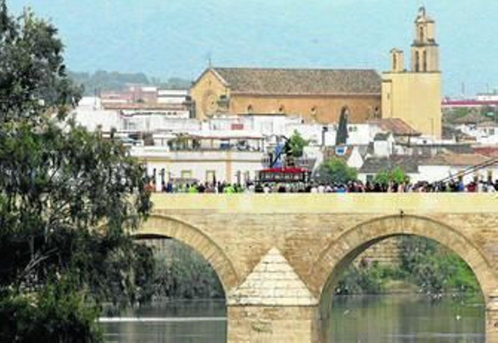 El Señor de los Reyes cruza el Puente Romano con la parroquia de San Pedro al fondo.