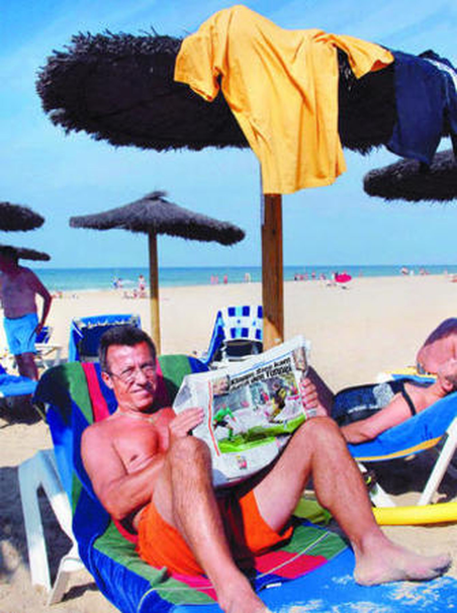 Un turista alemán lee la prensa en una playa cercana a un hotel del Novo.