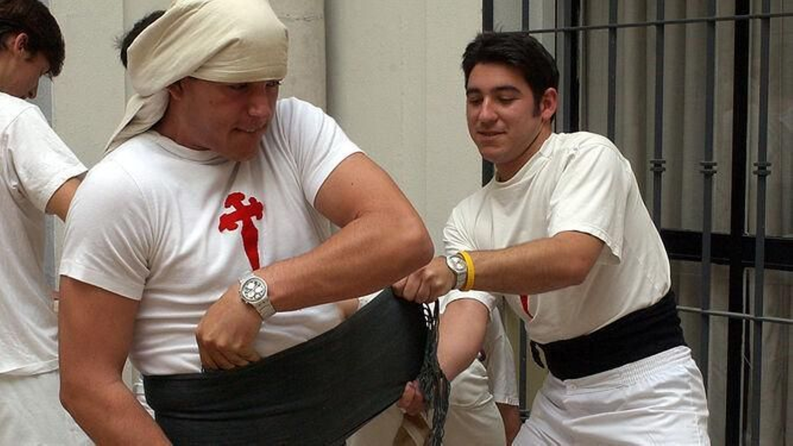 Un costalero ayuda a otro a ponerse bien la faja