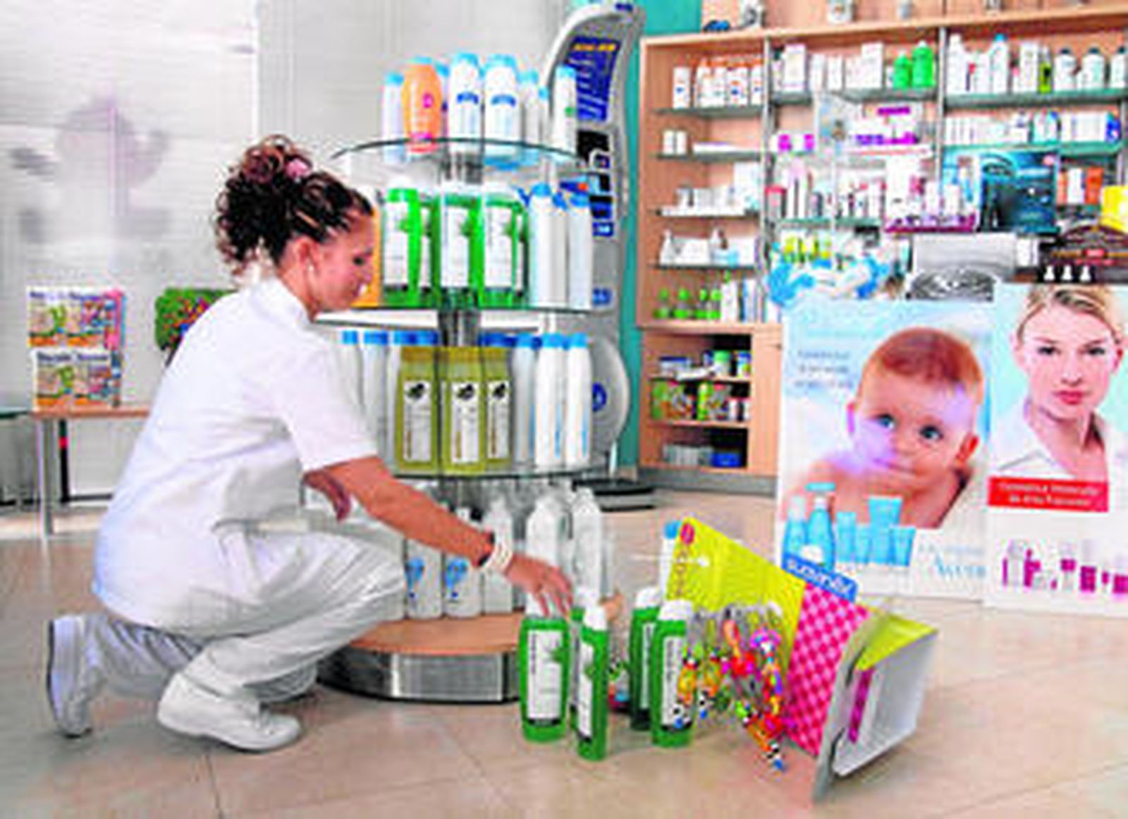 Una dependienta de una farmacia de Chiclana vuelve a poner en su sitio los productos que los terremotos tiraron de las estanterías.