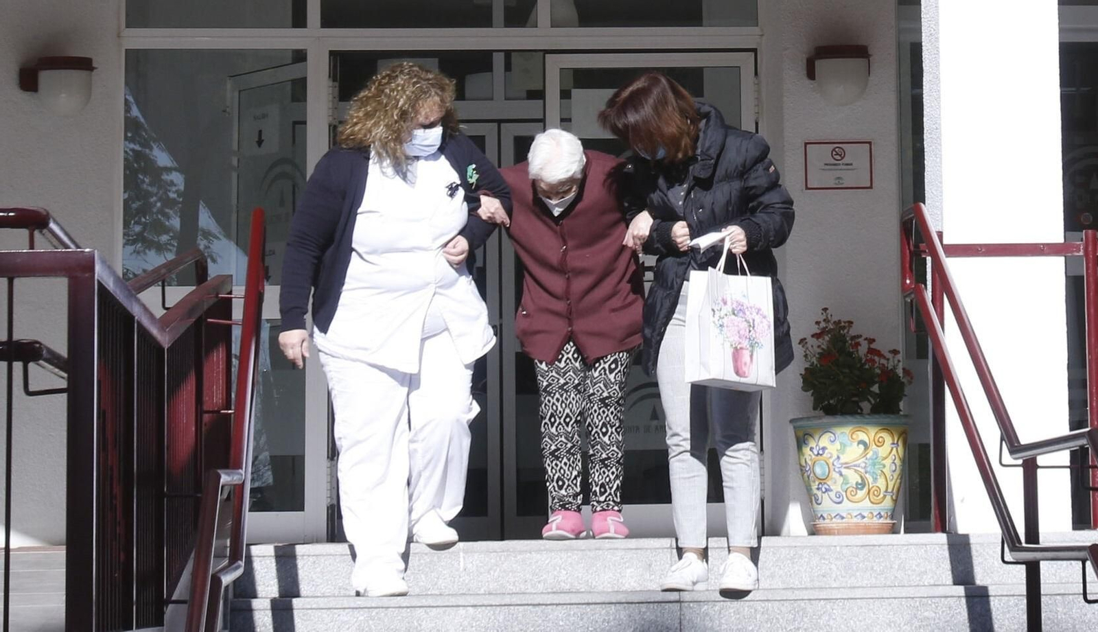 Una mujer es acompañada por una empleada y un familiar a las puertas de una residencia de mayores.