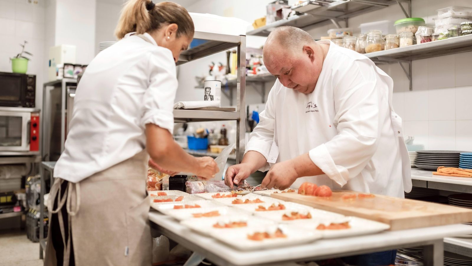 Carlos López emplatando en su cocina junto a una ayudante