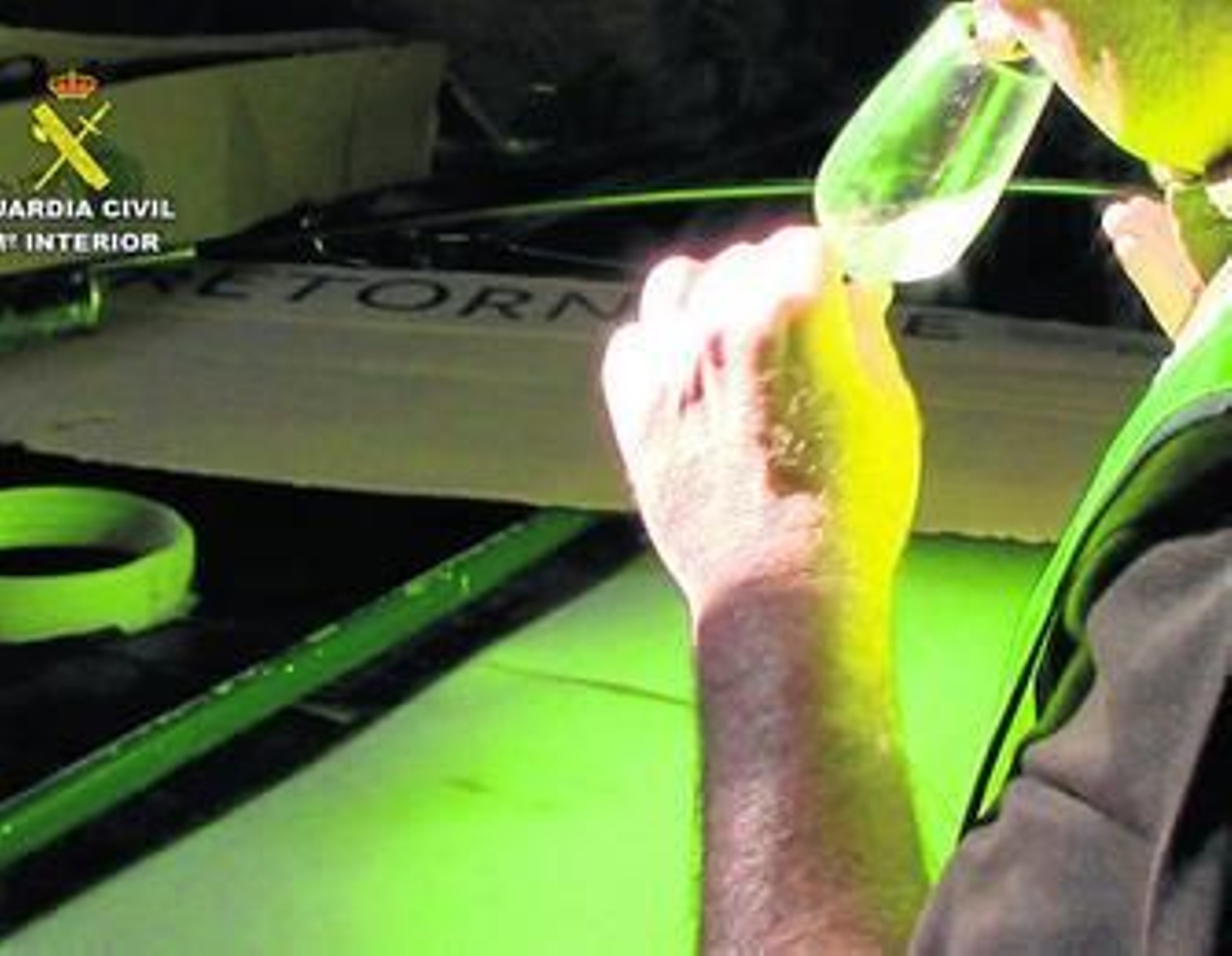 Un agente del Seprona junto a los contenedores de plástico en los que se almacenaba el vino en la bodega clausurada.