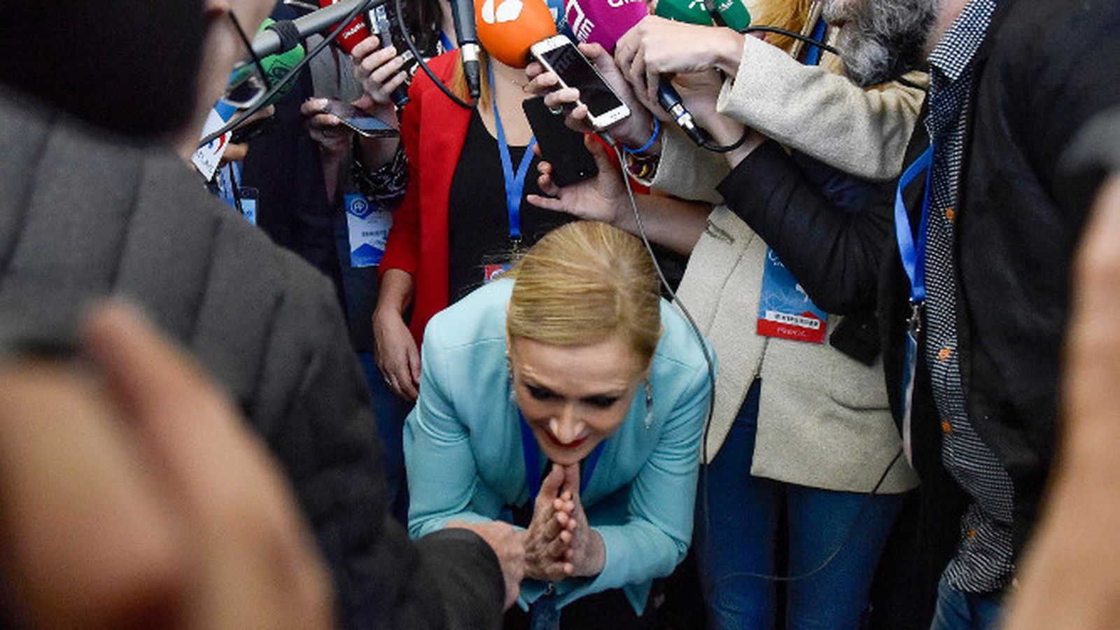 Cifuentes pasa agachada entre los periodistas.