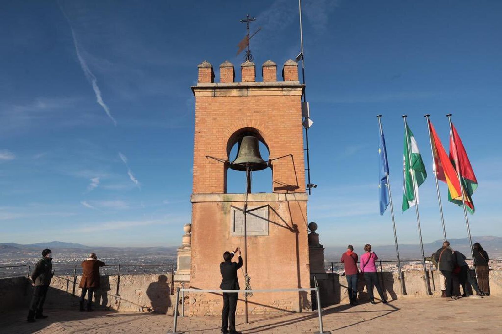 Un trabajador de la Alhambra hace sonar la campana de la Torre de la Vela para mantener la tradición.