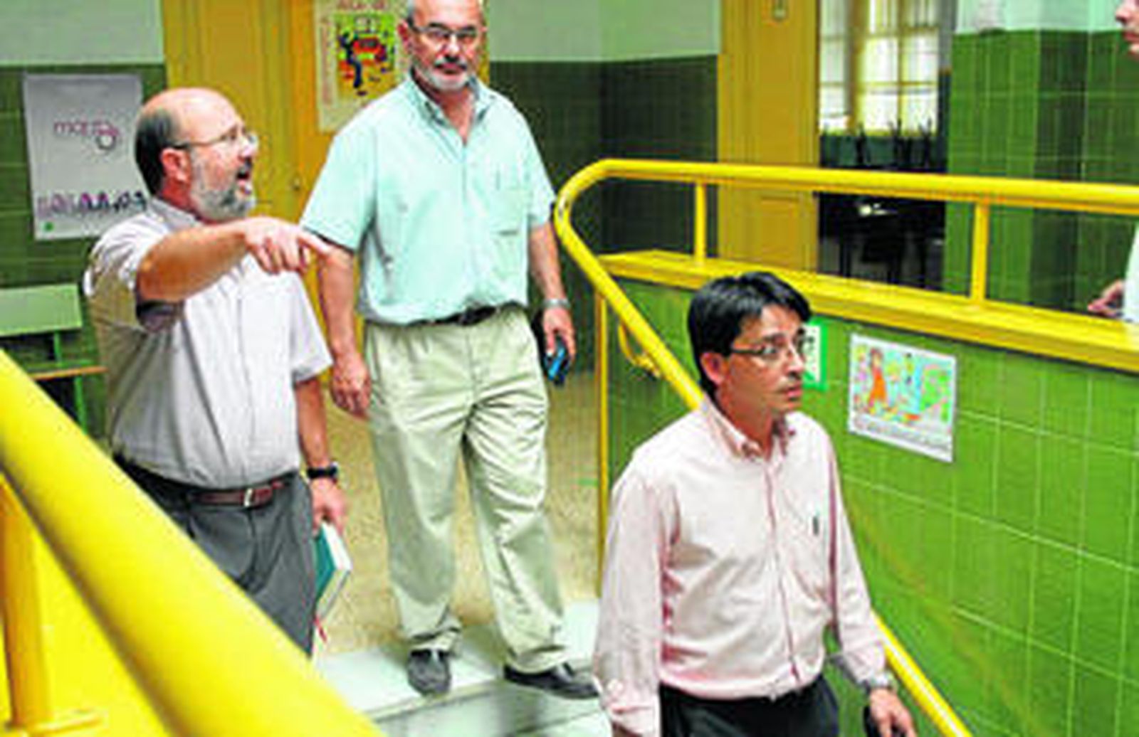 Rafael Suárez, enseña a José Santiago y Manuel Guzmán los desperfectos del colegio del que es director.