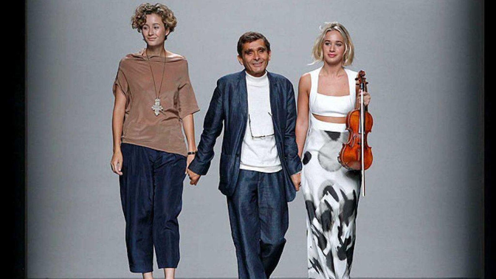 El diseñador de Orense, saludando de la mano de dos de sus modelos al final de un desfile.