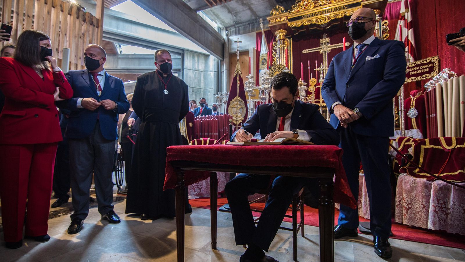 El presidente de la Junta, Juanma Moreno, firma en el libro de honor de la hermandad de los Afligidos.