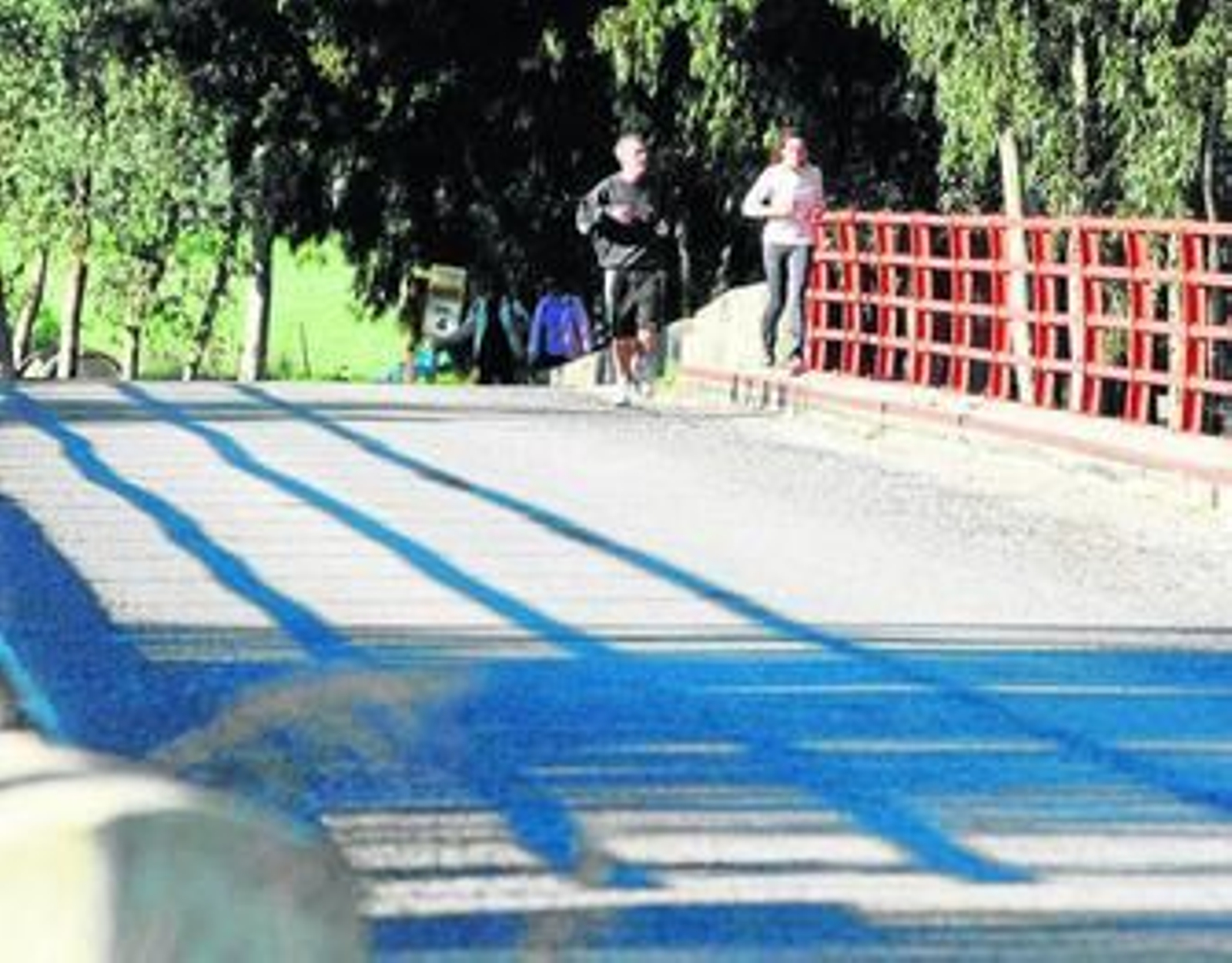 Varias personas cruzan el río Palmones por el arcén de la calzada.
