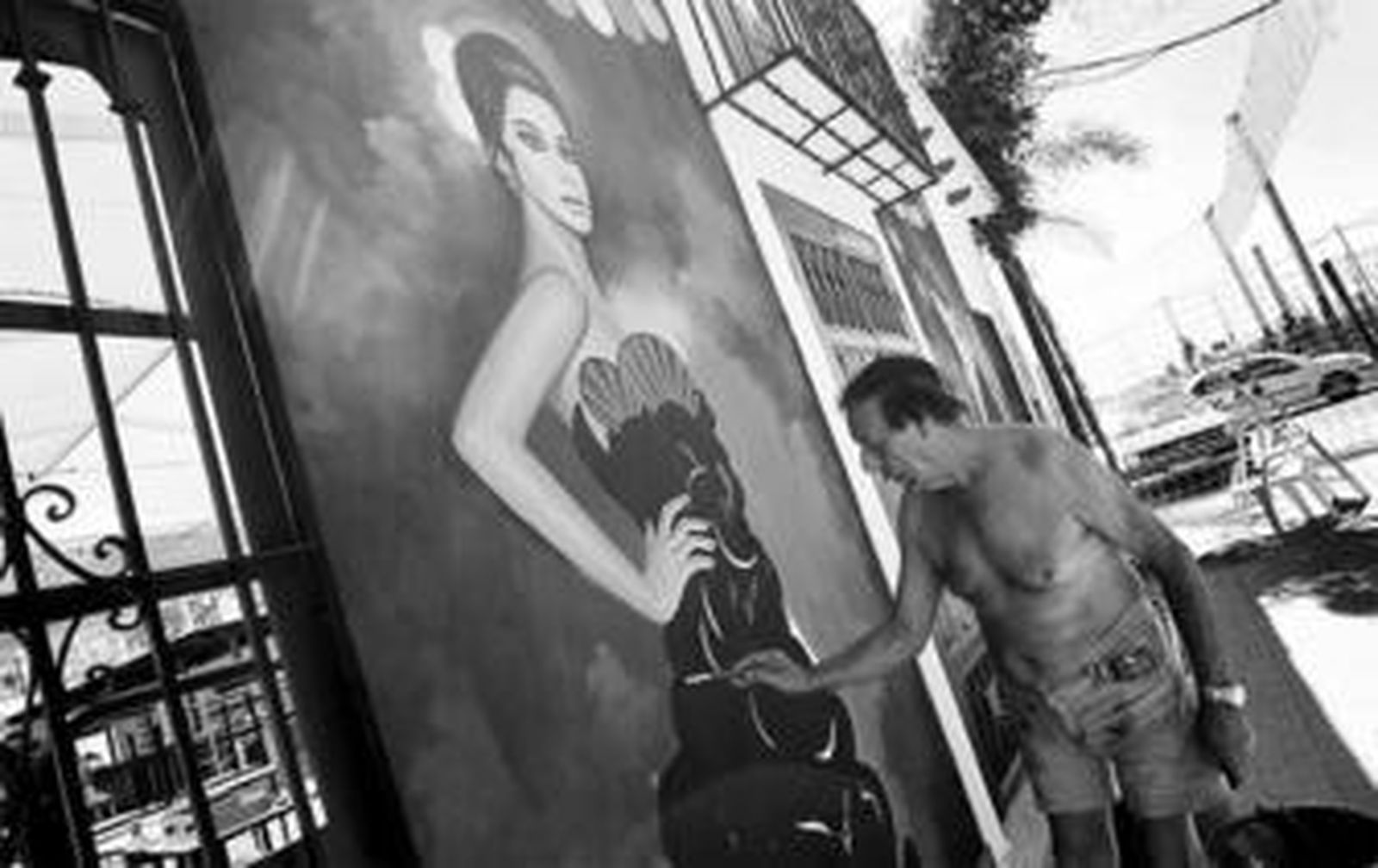 Un particular retoca la pintura de uno de los murales que adornan una fachada.