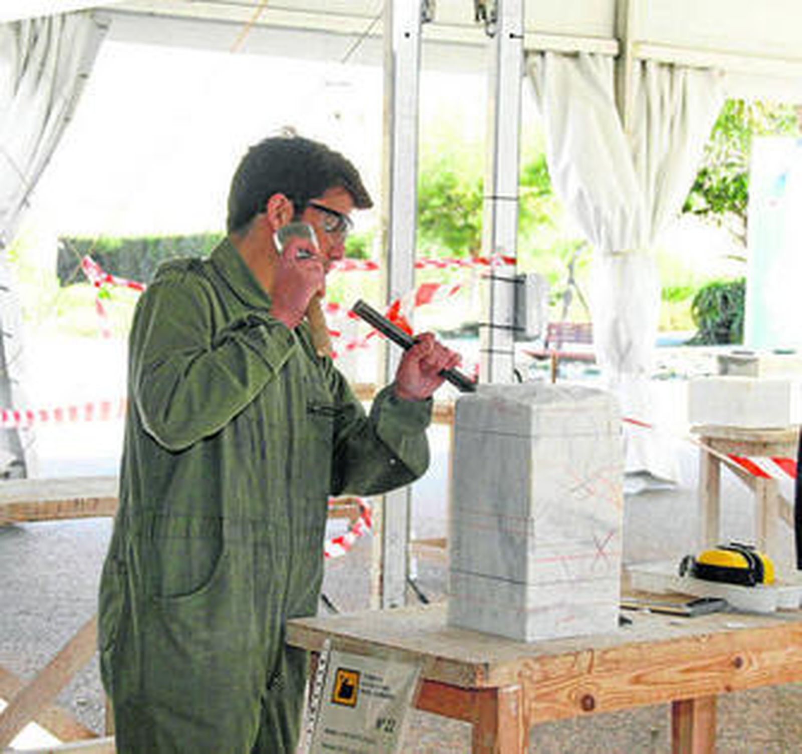 Un joven escultor sostiene el martillo y el cincel entre sus manos.
