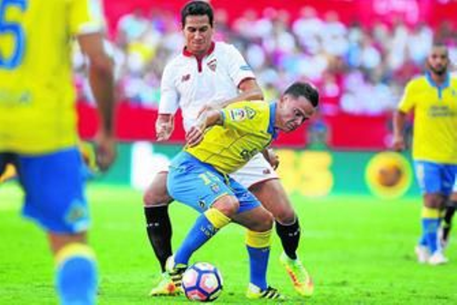 Ganso intenta presionar a Roque Mesa, encorvado para proteger la pelota.