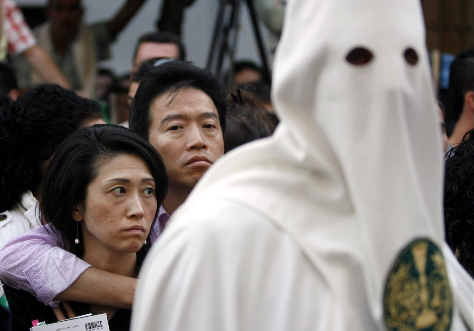 Dos turistas asiáticos observan una procesión de la Semana Santa cordobesa.