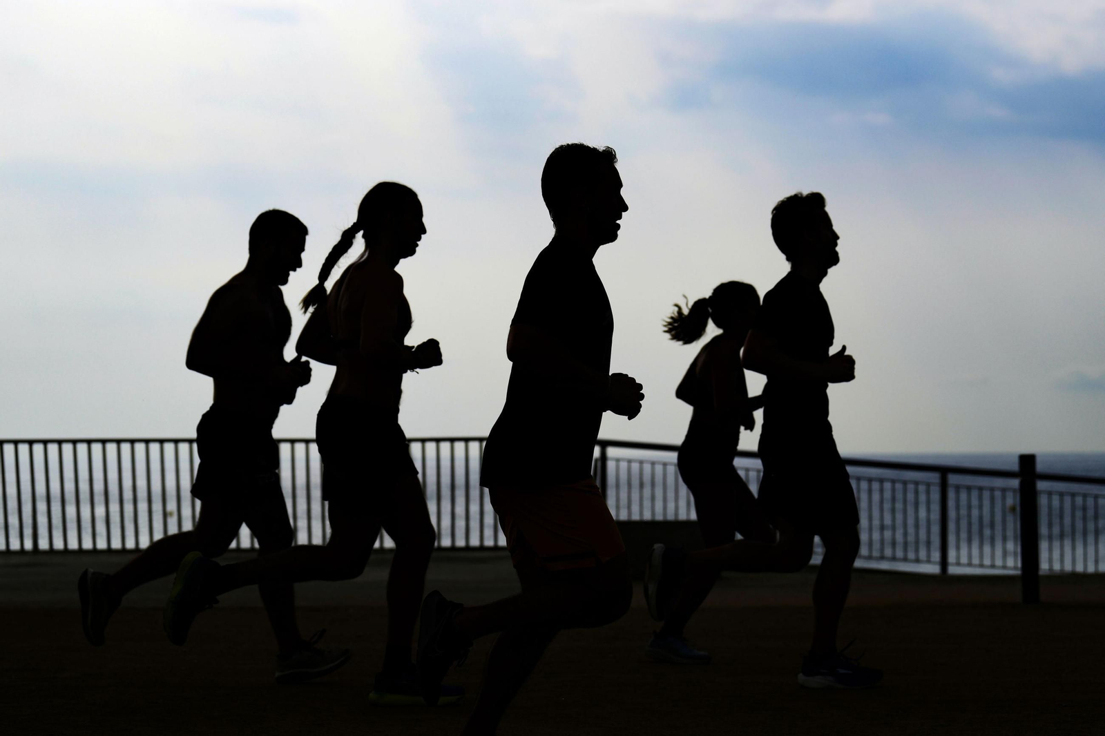 Un grupo de corredores realizan carrera continua en el Paseo Marítimo de una ciudad española.
