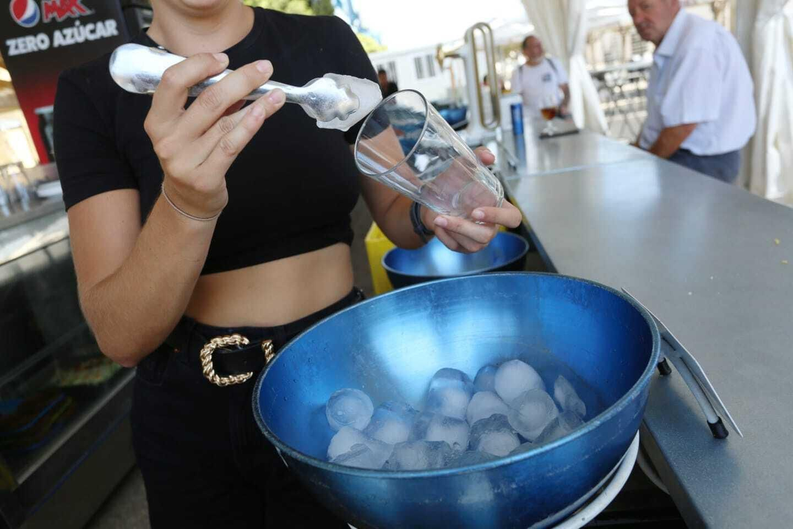 Una camarera prepara una bebida con cubitos de hielo.