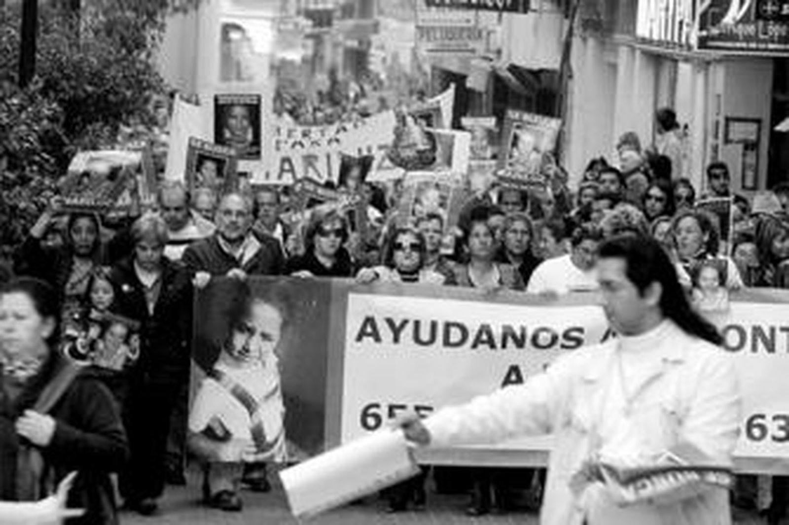 Un vecino reparte fotografías de Mari Luz en la cabecera de la manifestación que ayer recorrió de nuevo Huelva para exigir la vuelta de la menor.