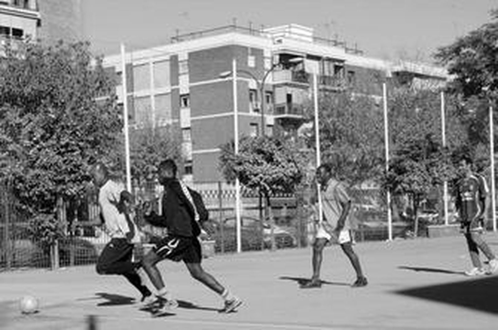 Dos nigerianos persiguen la pelota ante la atenta mirada de un compatriota y de Yusuf, un marroquí sevillista con camiseta del Madrid.