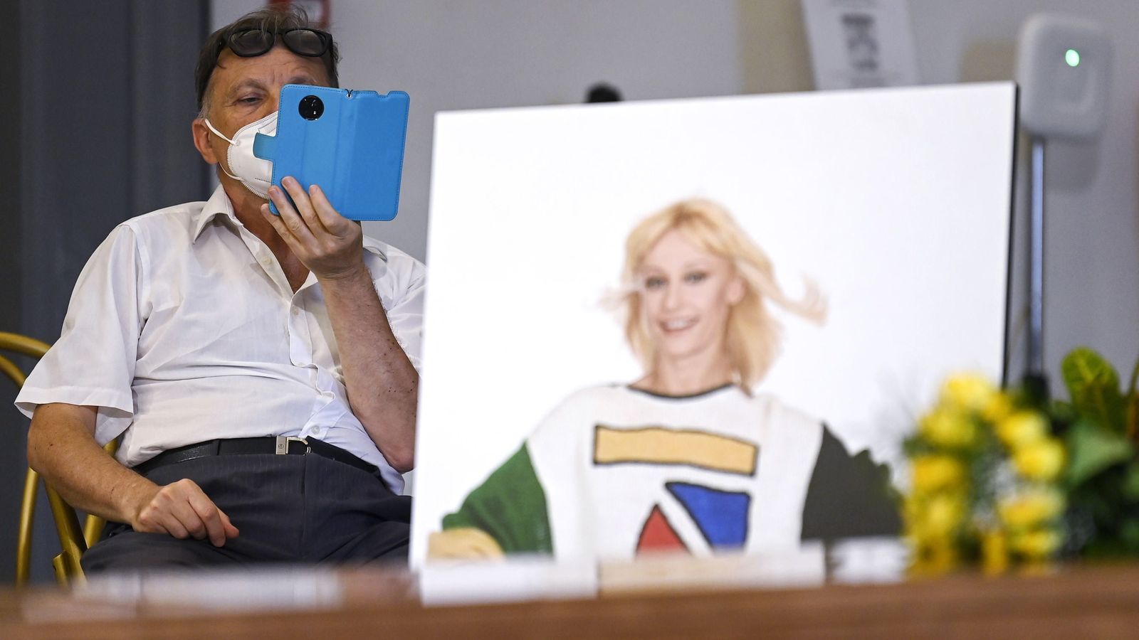 Uno de los visitantes hace fotos al féretro con una foto de Raffaella Carrá.