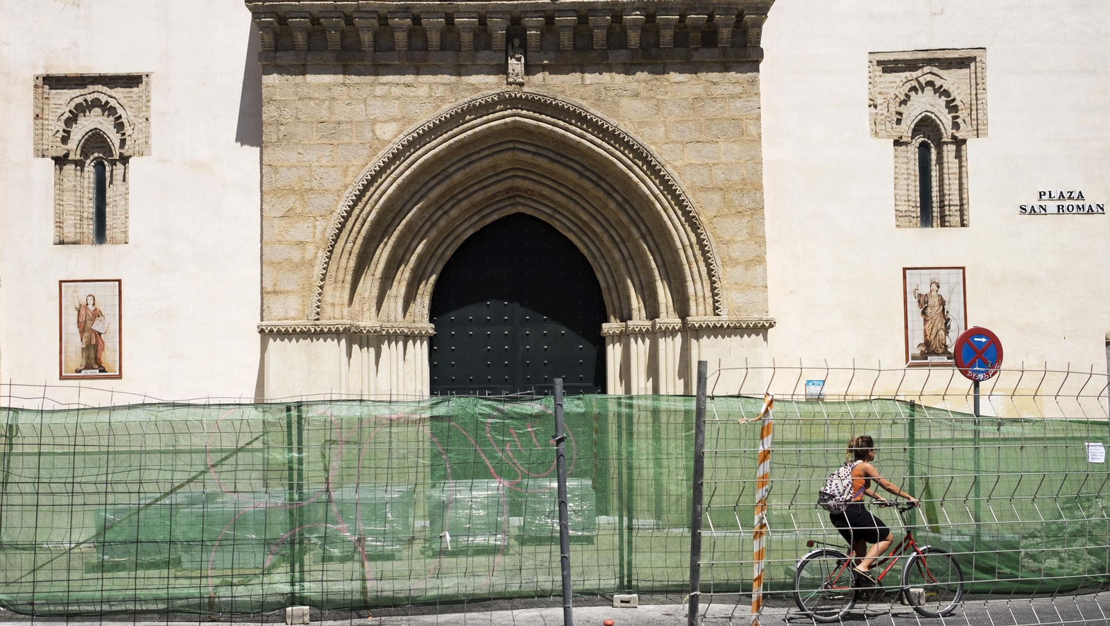 Una ciclista pasa junto a la obra que se realiza en la Plaza de San Román.