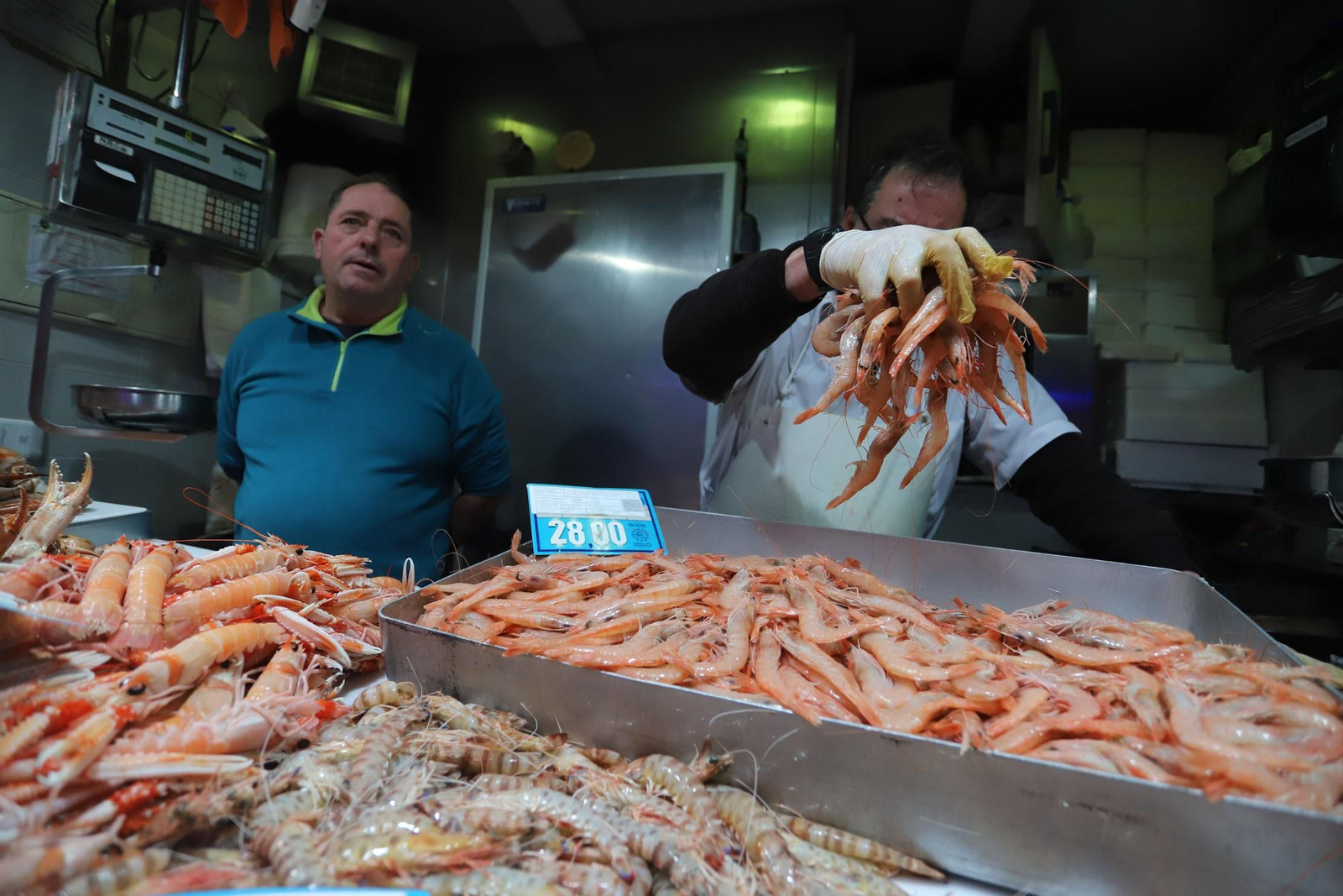 Uno dependiente del Mercado del Carmen coge un puñado de gambas con un precio de 28 euros el kilo, en los días previos a la cena de Nochebuena.