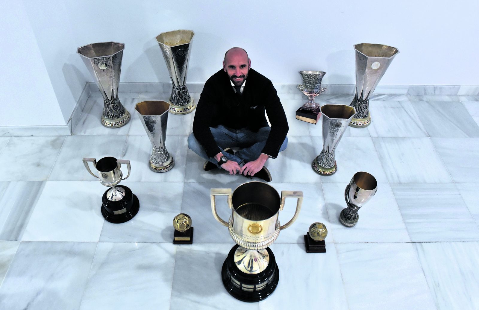 Monchi posa con los nueve títulos y los dos trofeos de mejor equipo del mundo.