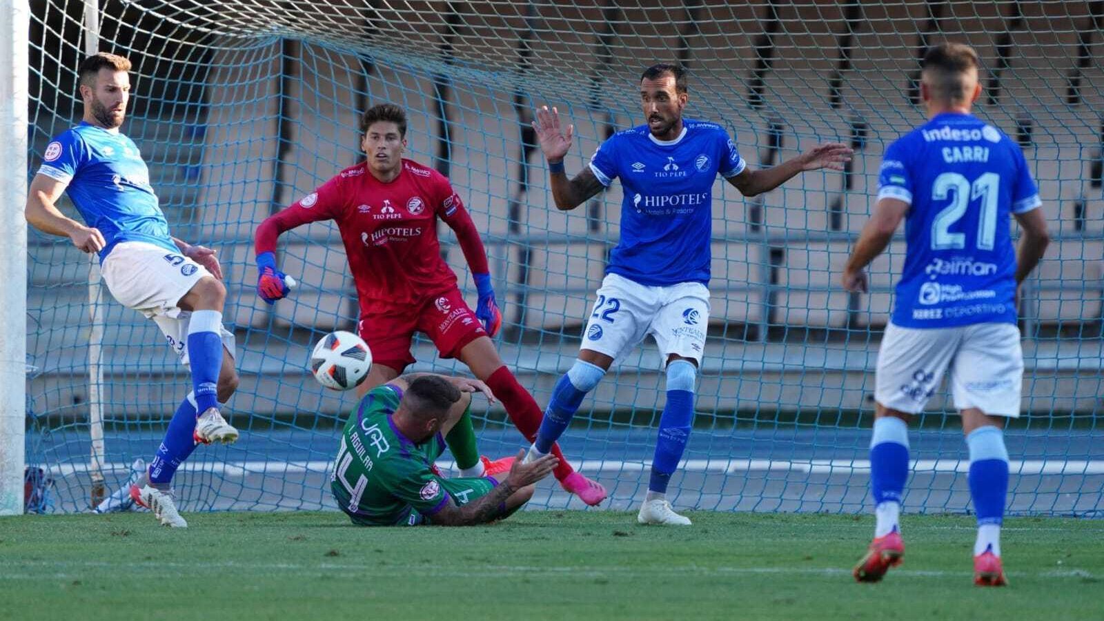 Oca despeja el balón con Iván Aguilar en el suelo. Oca despeja el balón con Iván Aguilar en el suelo.