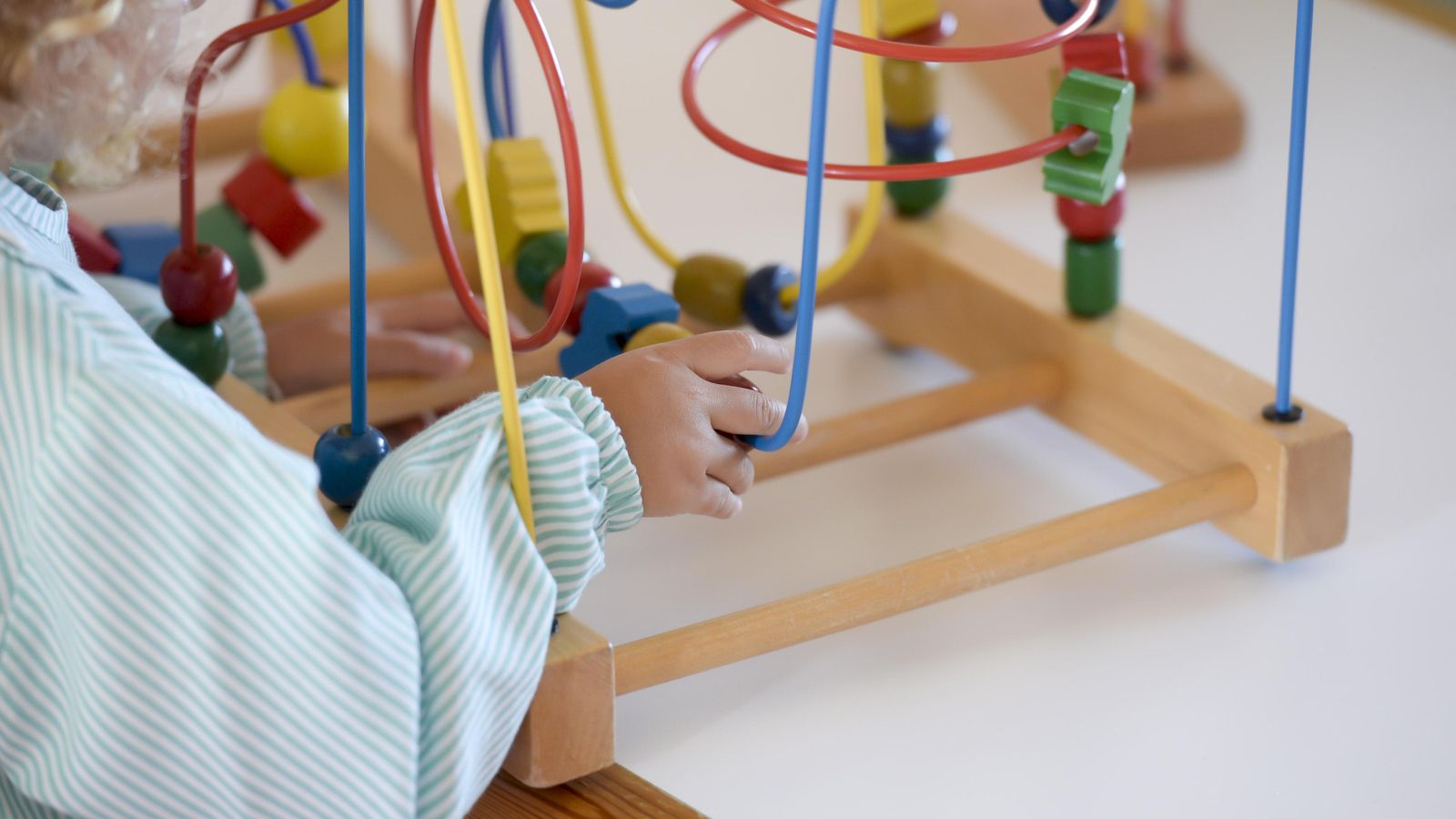 Una menor manipula un juguete educativo en una guardería.